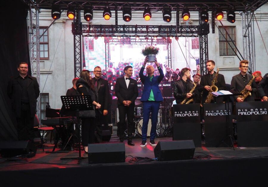 Koncert „Brzmienia Krakowa” w Wilnie - na scenie instrumentaliści i dyrygent Małopolskiego Big Bandu. Artyści stoją z instrumentami, dyrygent wznosi kwiaty do publiczności