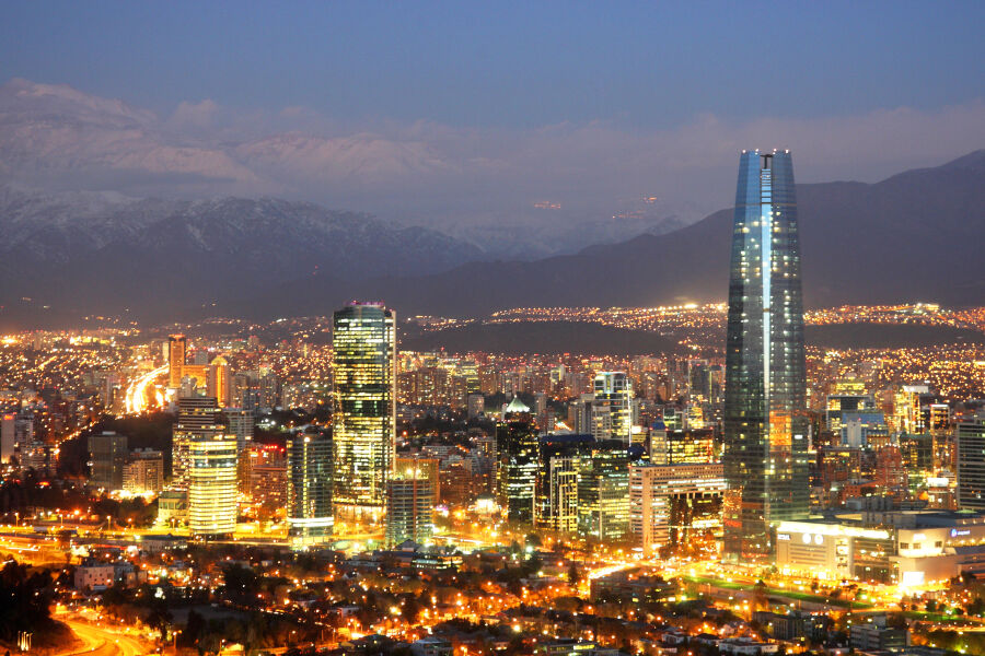 Santiago de Chile - stolica Chile - widok miasta nocą. Wysokie, mocno oświetlone wieżowce na tle wysokich gór