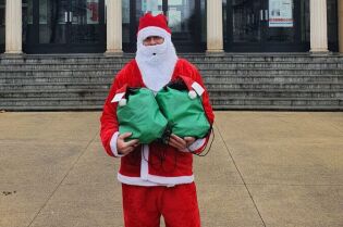 Zdjęcie przedstawia Świętego Mikołaja trzymającego prezenty