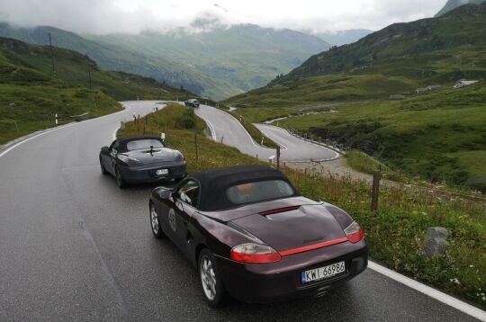 samochody marki Porsche na krętej asfaltowej drodze w górach