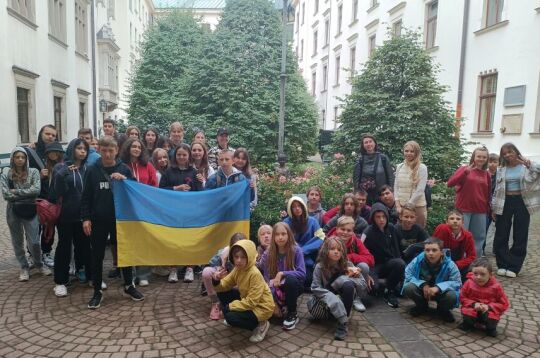 Wizyta dzieci z Kijowa. Grupa z przewodnikiem przy rzeźbie Anny Kijowskiej na dziedzińcu krakowskiego magistratu. 